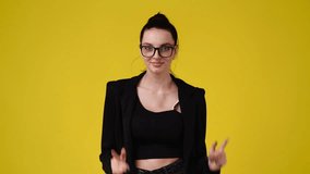 4k slow motion video of one girl pointing at camera and showing thumb up over yellow background.