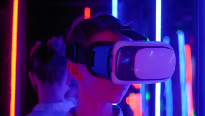 VR, futuristic, retrowave, immersive, entertainment concept. Slow motion: woman using virtual reality headset and looking around at interactive technology exhibition with colorful illumination Royalty-Free Stock Footage #1098964867