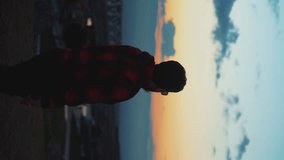 A man on the background of sunset in a lumberjack hoodie. Vertical video