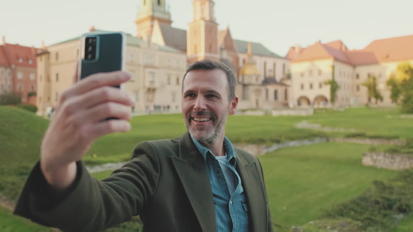 Man takes selfie on mobile phone on the old city background