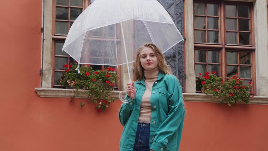 Rain stopped, young woman with umbrella rejoicing near house outdoors, low angle view