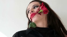 Makeup on the face to celebrate Carnival in Brazil. Portrait of a zombie woman with a rose flower