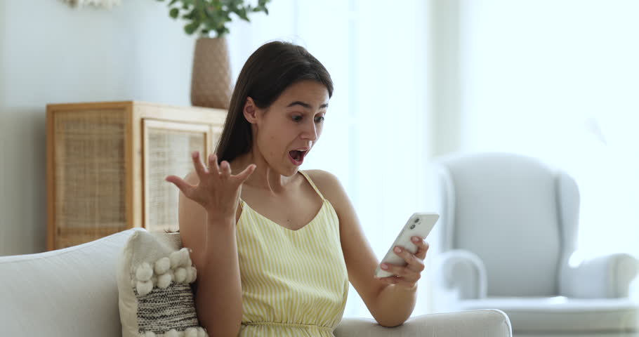Emotional happy young woman looks at smartphone screen, reading message with unbelievable amazing news, celebrating fantastic offer getting, enjoy sell-out, huge discounts or lottery win notification | Shutterstock HD Video #1098976631