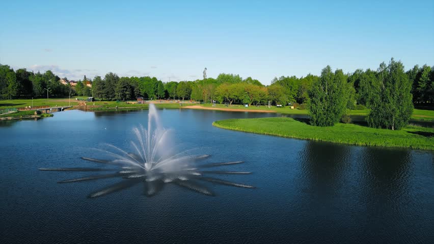 Fountain located in a lake within a city park. It showcases the urban landscape, highlighting the presence of nature in the city. The fountain and the park offers outdoor recreation and relaxation.