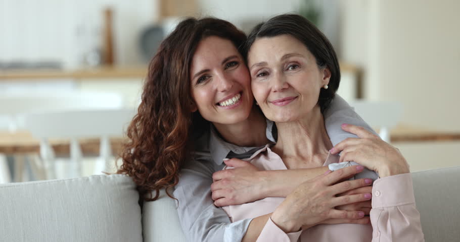 Close up older and younger women, grown up 35s female cuddling her senior 50s mother smile pose look at camera enjoy time together, hugging feeling warmth and love. Multigenerational family portrait Royalty-Free Stock Footage #1098982667