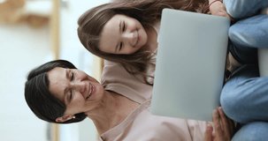 Granny and little granddaughter use laptop spend weekend leisure at home on internet, watch videos, new vlog, educational content or cartoons on-line, discuss purchase, buy through e-commerce website