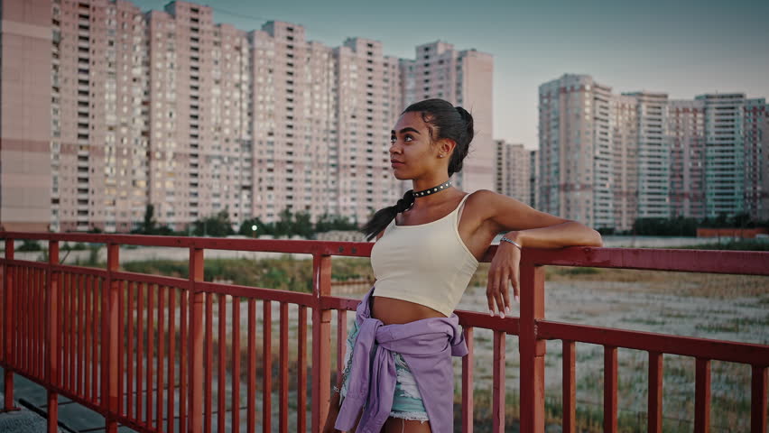Urban youth lifestyle. Cool young black woman relaxing outdoors, feeling free and self confident, posing in urban residential district alone, tracking shot | Shutterstock HD Video #1098983423