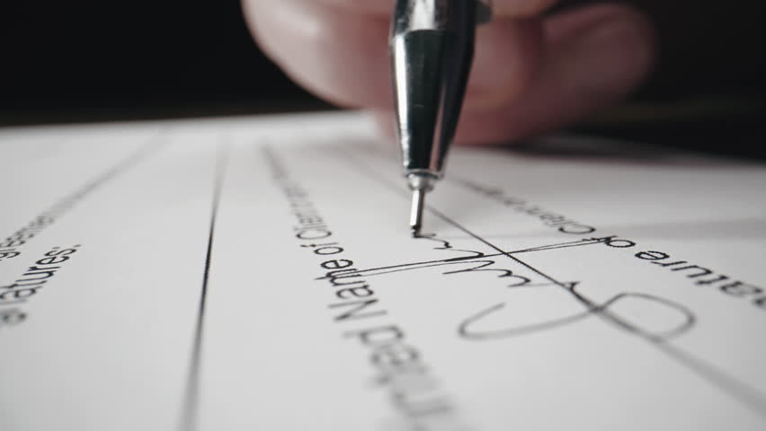Close-up of male hand putting his signature on the document or contract, signing report after checking information. Business agreement, Concluding contract. Closing deal. Sign.