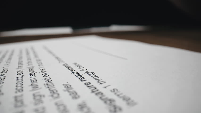 Close-up of a document or contract and cropped view of a hand putting signature, signing document. Business agreement. Successful deal.