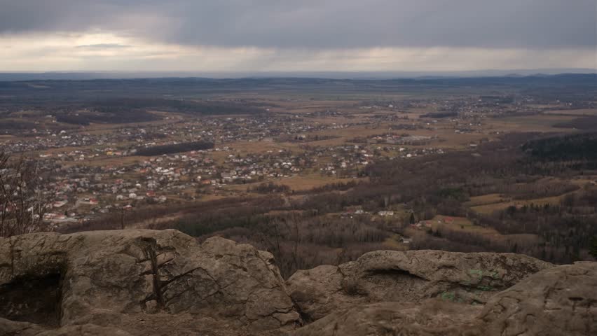 a male tourist with a backpack enjoys the view of the city from the mountain 
