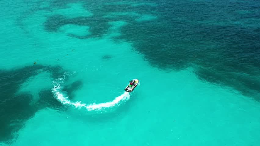Aerial view of Personal watercraft (PWC), also called water scooter rushes through the waves of the Caribbean Sea. Aerial view. Royalty-Free Stock Footage #1098990763