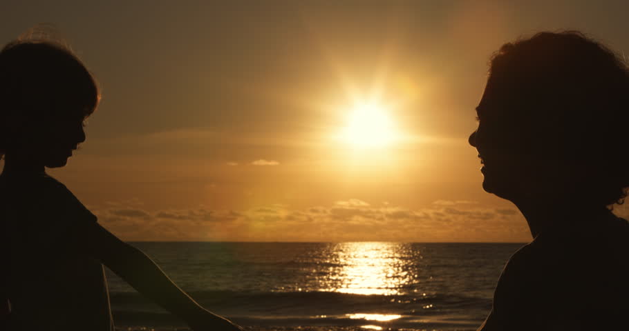 mother and little son silhouette at sunset, sun flare shot Hands of woman and her child made a heart shape, close up emotional family scene, happy childhood and happy family concept, human emotions