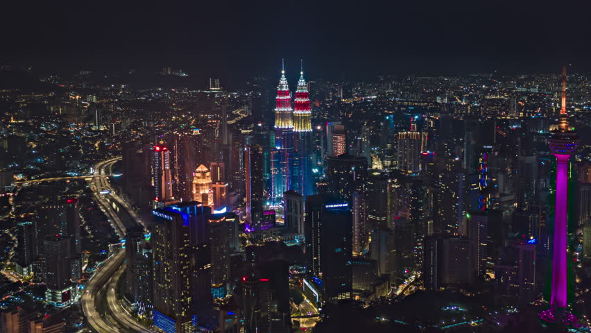Malaysia Time lapse: Aerial view during night overlooking KL city skyline with Malaysia flag colors with busy streets. Zoom out motion timelapse. Prores 4KUHD.