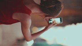 VERTICAL VIDEO: Close-up, girl takes pictures of downtown mobile phone. Closeup of young woman shoots the cityscape on smartphone in the evening time. Back view