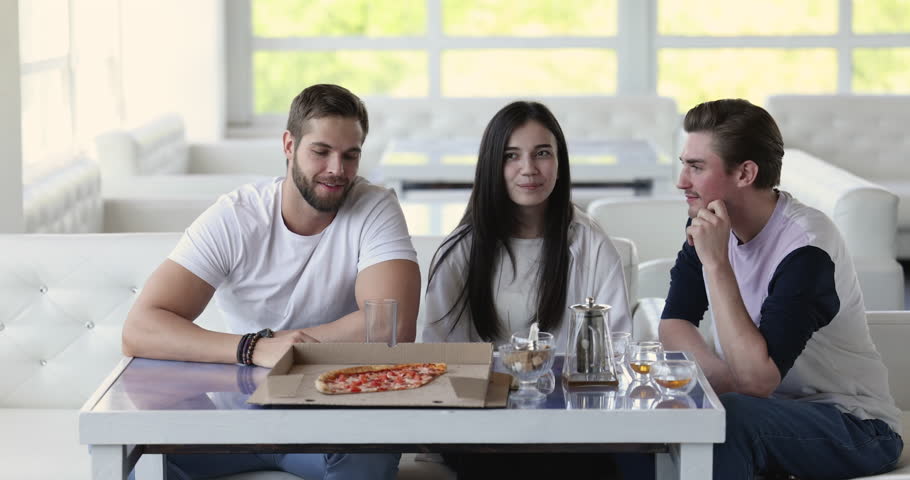 Man visit restaurant with friends, raise arm call the waiter to make order. Indian waitress in apron write in notepad, take order talks to group of young positive people cafe clients. Customer service