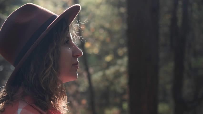 A young woman breathes clean air, looks at the sky with a smile, walks with pleasure in the autumn forest