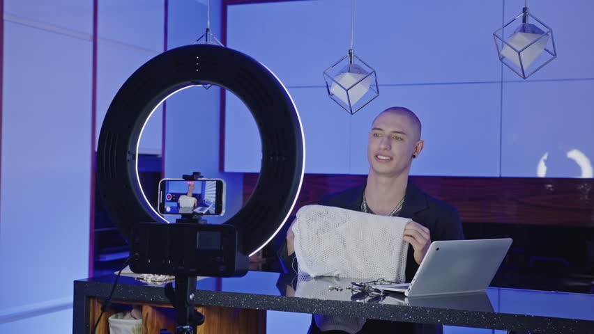 Man blogger talking on camera and recording himself with phone in the studio. High quality 4k footage