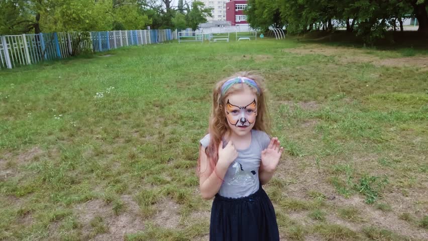 Little girl with face painting. She happily dances imagining herself as a fox.