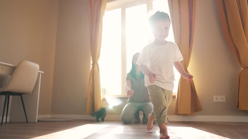 Happy family. Baby takes first steps. Mom teaches baby to walk at home. Child runs across floor. Maternal support. Mom teaches child to run and walk. Cheerful kid with smile runs at home on laminate | Shutterstock HD Video #1099009107