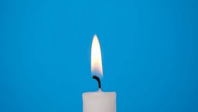 A white candle burning on a blue background. A candle is blown out, beautiful smoke from a blown out candle on a blue background 4K resolution video.