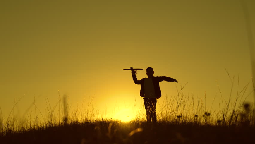 Boy child Aviator runs with toy plane across field in rays of sunset. Child wants to become an astronaut pilot. Children play with toy plane. Teenager dreams of flying becoming pilot. Freedom concept | Shutterstock HD Video #1099013283