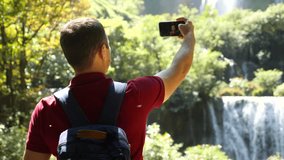 Modern social media content maker, influencer talk on video, shoot blog on mobile phone outdoors. Adult man blogger and vlogger recording selfie movie on his smartphone at nature, look at camera.