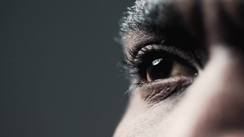 Eyes of African American Black Man Looking at Side in Extreme Close-up. Beautiful Iris and Pupil of Eyeball with Lens Eyelid with Lashes. Macro Zoom Image Optical Cornea and Eye Retina of Male Indoor