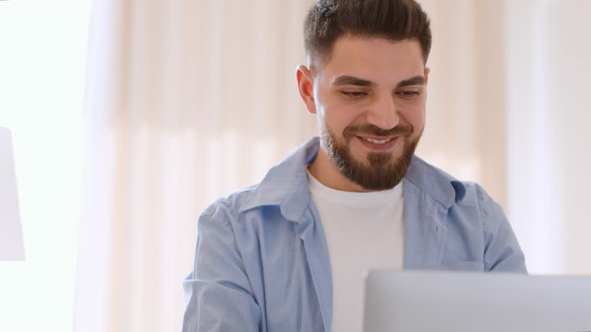 Happy freelance work. Close up portrait of young middle eastern guy digital nomad typing on laptop computer, enjoying his remote work at home office, tracking shot, slow motion, free space | Shutterstock HD Video #1099018077