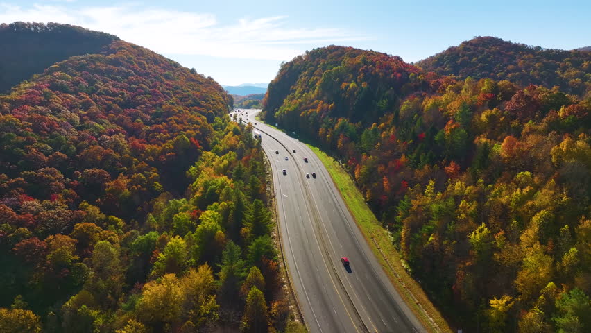 I-40 freeway in North Carolina leading to Asheville through Appalachian mountains in golden fall with fast moving trucks and cars. Interstate transportation concept