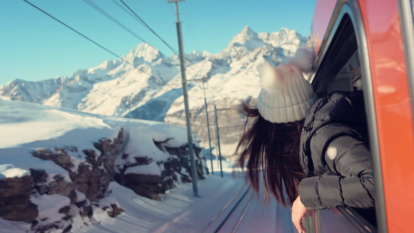 Happy woman traveler looks out from window traveling by train in beautiful winter mountains, Travel concept. Royalty-Free Stock Footage #1099028331