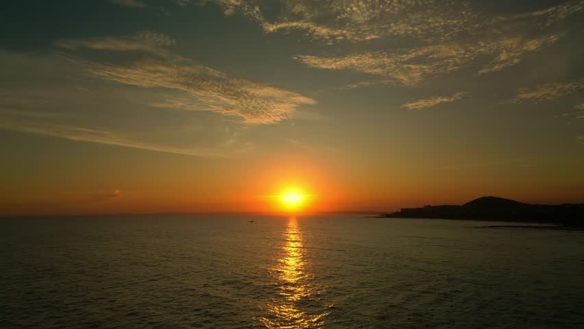 Shooting from a drone, flying along the sea against the background of a sunset and a fishing boat. Fishermen in the sea are fishing at sunset. Beautiful calm sunset with only one yacht on the sea | Shutterstock HD Video #1099029307