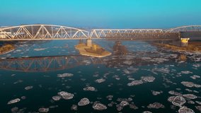 Reflection in water with floating ice floes of retro style metal bridge over river in frozen winter. Beautiful snowy landscape in cold times. Concept of nature ecology preserving - Powered by Shutterstock - Get 15% off with code: PIKWIZARD15