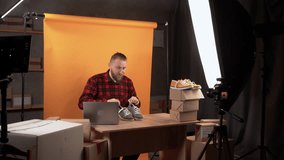 business owner is sitting in a home video studio recording a review of goods for an online store. looks into the camera makes a test drive of sports shoes. Business social media influencer.