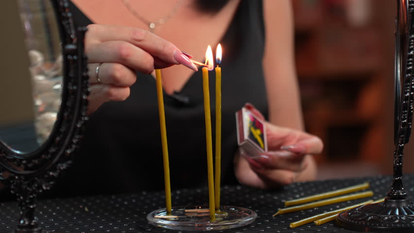 woman magician ignites candles with a match. magic ritual with candles and mirrors. divination ritual on mirrors with candles. face is not visible. close-up Royalty-Free Stock Footage #1099035539