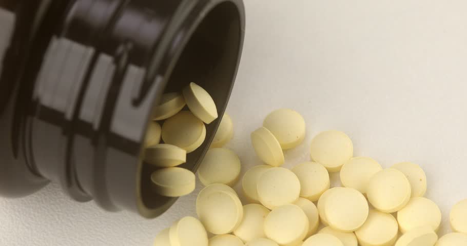 yellow pills spill out of the jar. brown packaging with medicines close-up. High quality 4k footage