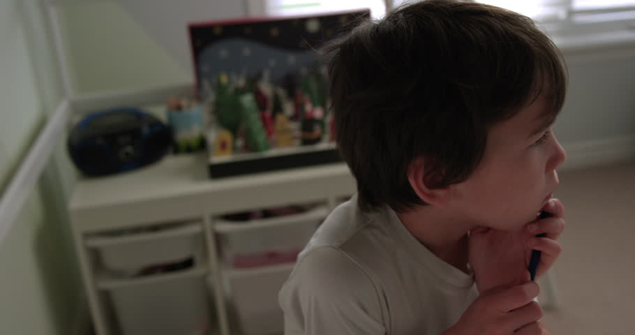 Young boy thinks about what he is going to write for homework in bedroom desk - medium shot | Shutterstock HD Video #1099036207