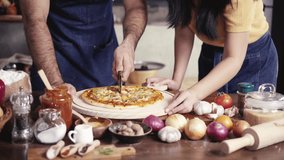 Young adult couple in small business pizza homemade restaurant, preparing pizza in the kitchen.
