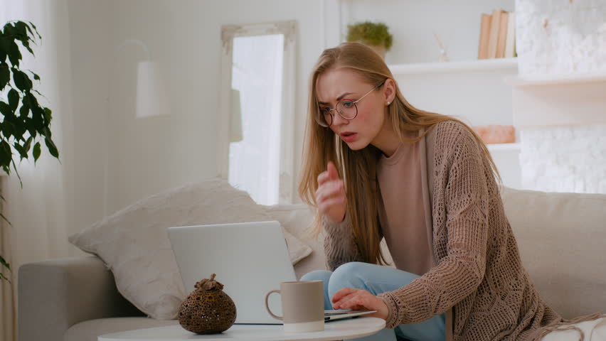 Caucasian shocked girl in glasses feel shock reading bad news woman lost with laptop worry about loosing online with computer terrible information mail Internet app problem business failure at home | Shutterstock HD Video #1099041897