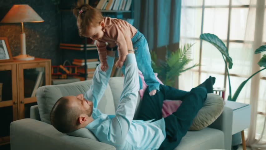 Happy day playing lifting baby daughter on sofa | Shutterstock HD Video #1099044201