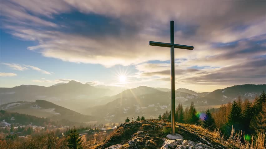Sunset over steel cross in rocky hill in spring rural nature with fast motion clouds sky Time lapse christian symbol