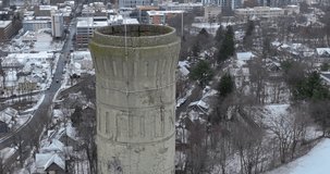 Winter aerial drone video slowly tilting camera while moving forward to look down the top of an industrial smoke stake. 