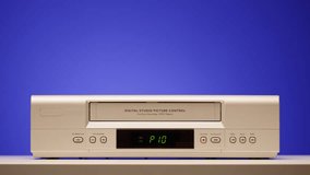 Old video recorder close-up, VHS. Retro player, vintage video cassette broadcasting on blue background, audio tape. 