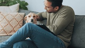 Young man with dog pet on sofa in his living room apartment for support, love and care. Happy guy relax on couch and smoke, kiss and play with his loyal puppy, animal or jack Russell terrier - Powered by Shutterstock - Get 15% off with code: PIKWIZARD15