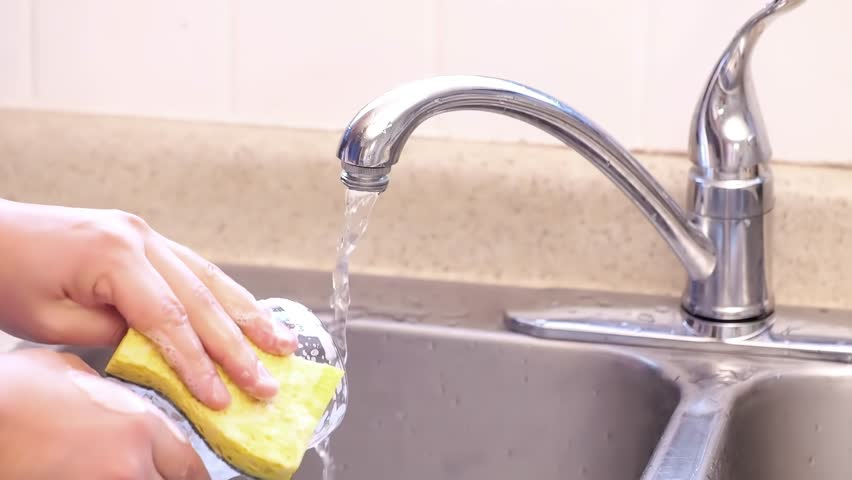 A person washing dishes with dish soap sponge and water at a kitchen sink. Royalty-Free Stock Footage #1099057261