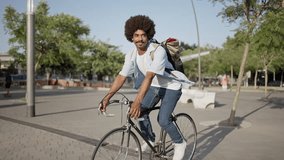 Young African American hipster man with bag riding bicycle on city street going to work  - Powered by Shutterstock - Get 15% off with code: PIKWIZARD15