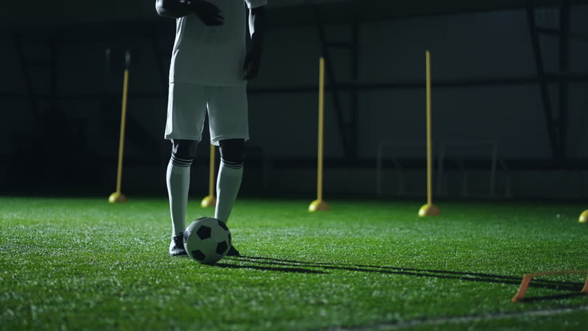 Black football player kicking ball by feet, training in sport hall, closeup view of legs of sportsman | Shutterstock HD Video #1099068091