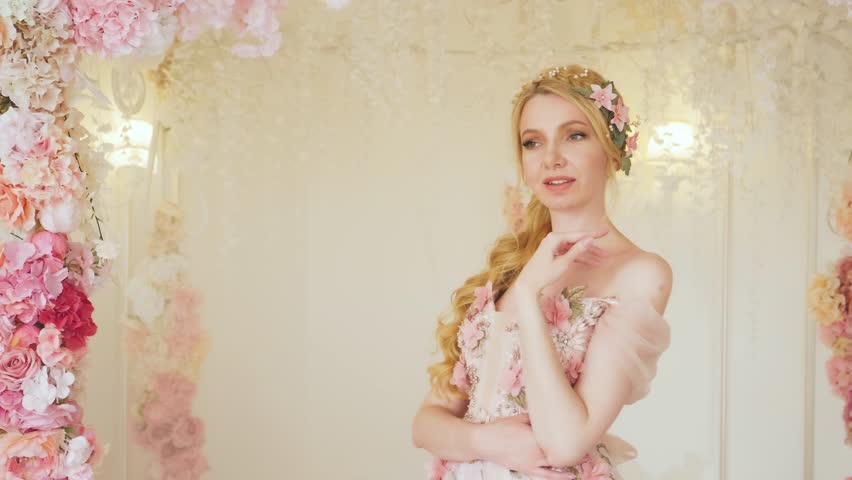 Fantasy portrait happy woman fairy princess, floral long evening dress wreath hairpin in blond hair. Flowers rose petals fall from above, holiday crackers. Girl smiling face. Wedding bride, arch decor Royalty-Free Stock Footage #1099068143
