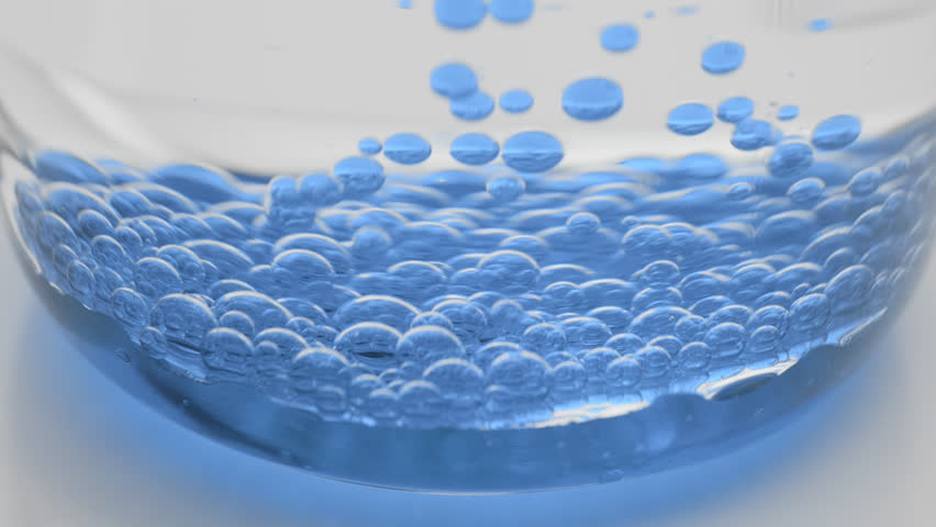 Side view extreme close-up shot of blue transparent bubbles sink to the bottom of beaker with water on grey background | Abstract face care cosmetics with blue tansy oil formulation concept | Shutterstock HD Video #1099068361