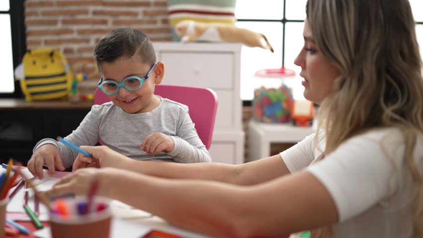 Teacher with boy and girl sitting on table drawing on paper at kindergarten Royalty-Free Stock Footage #1099069235