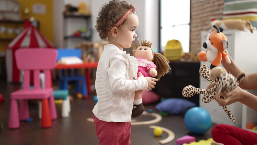 Teacher and toddler playing with dolls sitting on floor at kindergarten | Shutterstock HD Video #1099069407